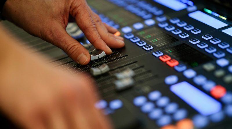 Hand adjusting controls on a professional audio mixing console