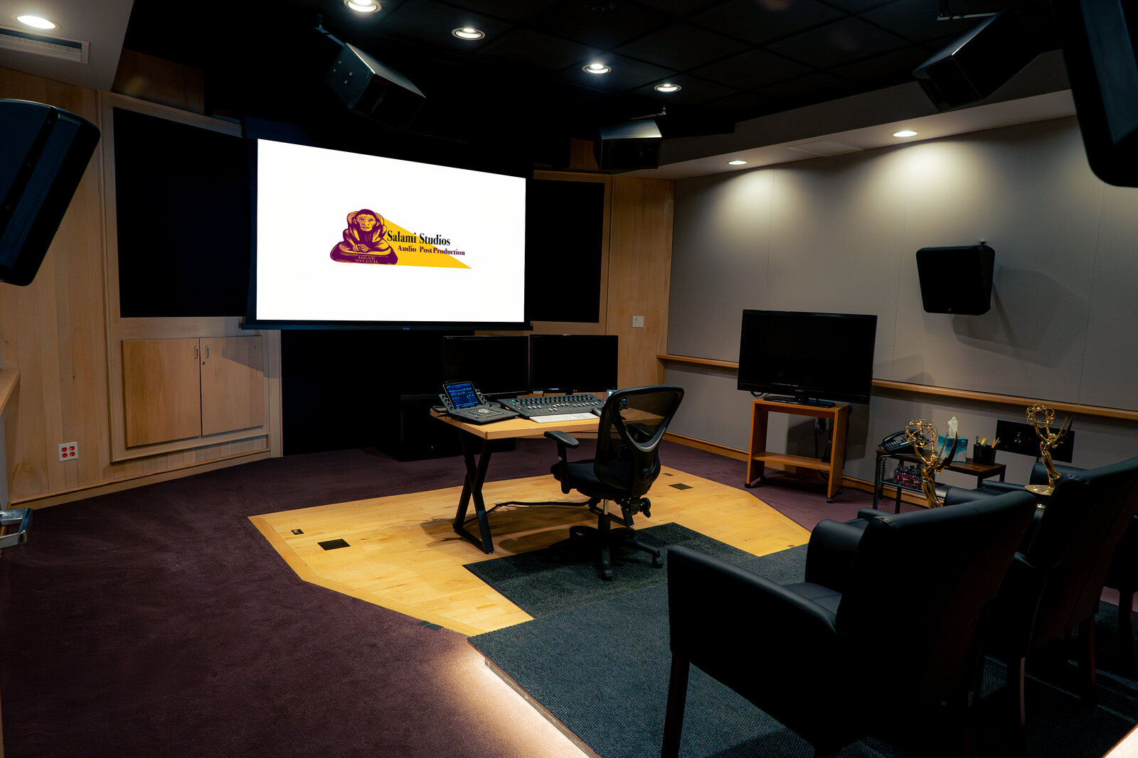 Studio B at Salami Studios, a Dolby Atmos mixing stage with a large screen showing the Salami Studios logo, a mixing desk and leather chairs. Image: Salami Studios