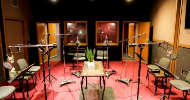 Studio C at Salami Studios in North Hollywood: a red-carpeted cast-record room with a ring of microphones on stands, music stands and chairs, and windows into the control room. Image: Salami Studios