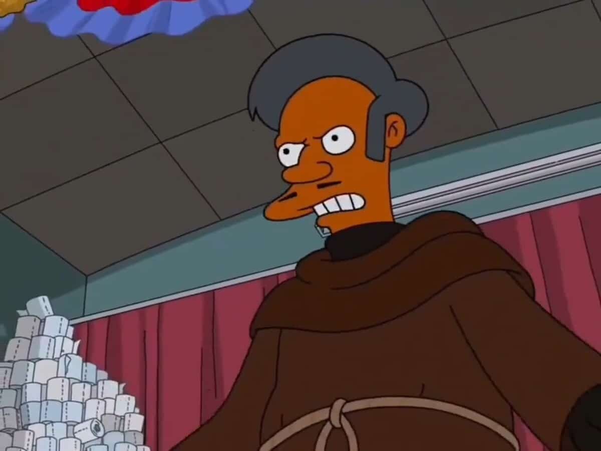Apu in a brown monk's robe in a Springfield hall, scowling, in The Simpsons episode The Revengening. Image: 20th Television Animation / Fox