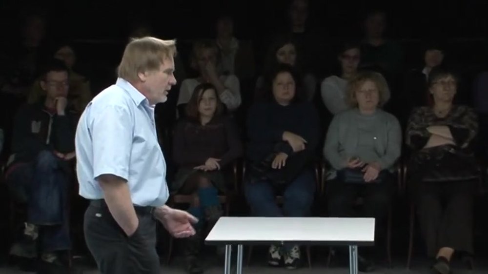 Jiří Štěpnička as Raymond in Blackbird on the National Theatre's Kolowrat stage, in a pale blue shirt with the audience seated close behind him. Image: Národní divadlo (YouTube)