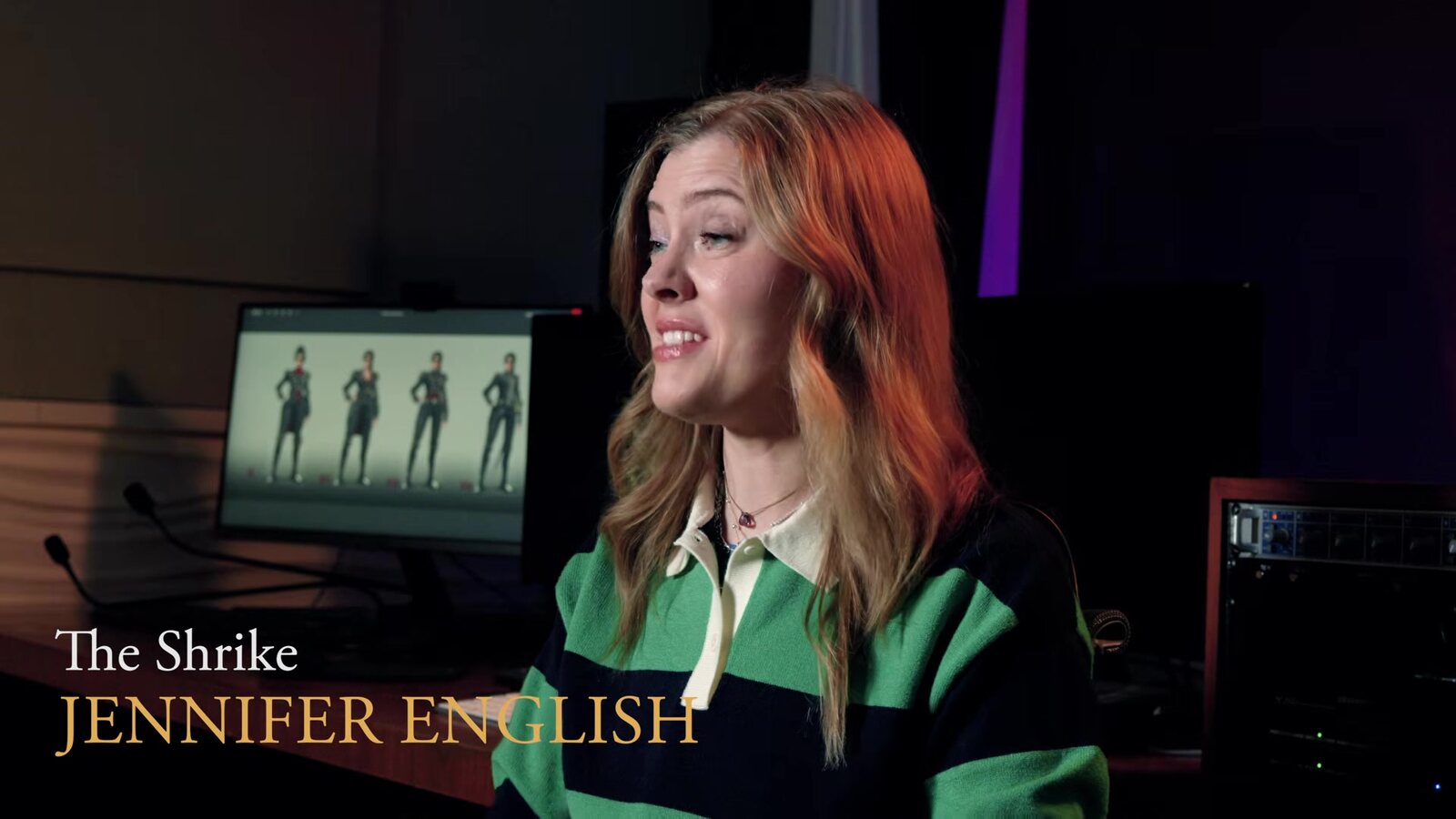 Jennifer English in a striped rugby shirt during her interview, with the name card The Shrike, Jennifer English and Shrike character art on the monitor behind her. Image: Lyrical Games, frame from the official film