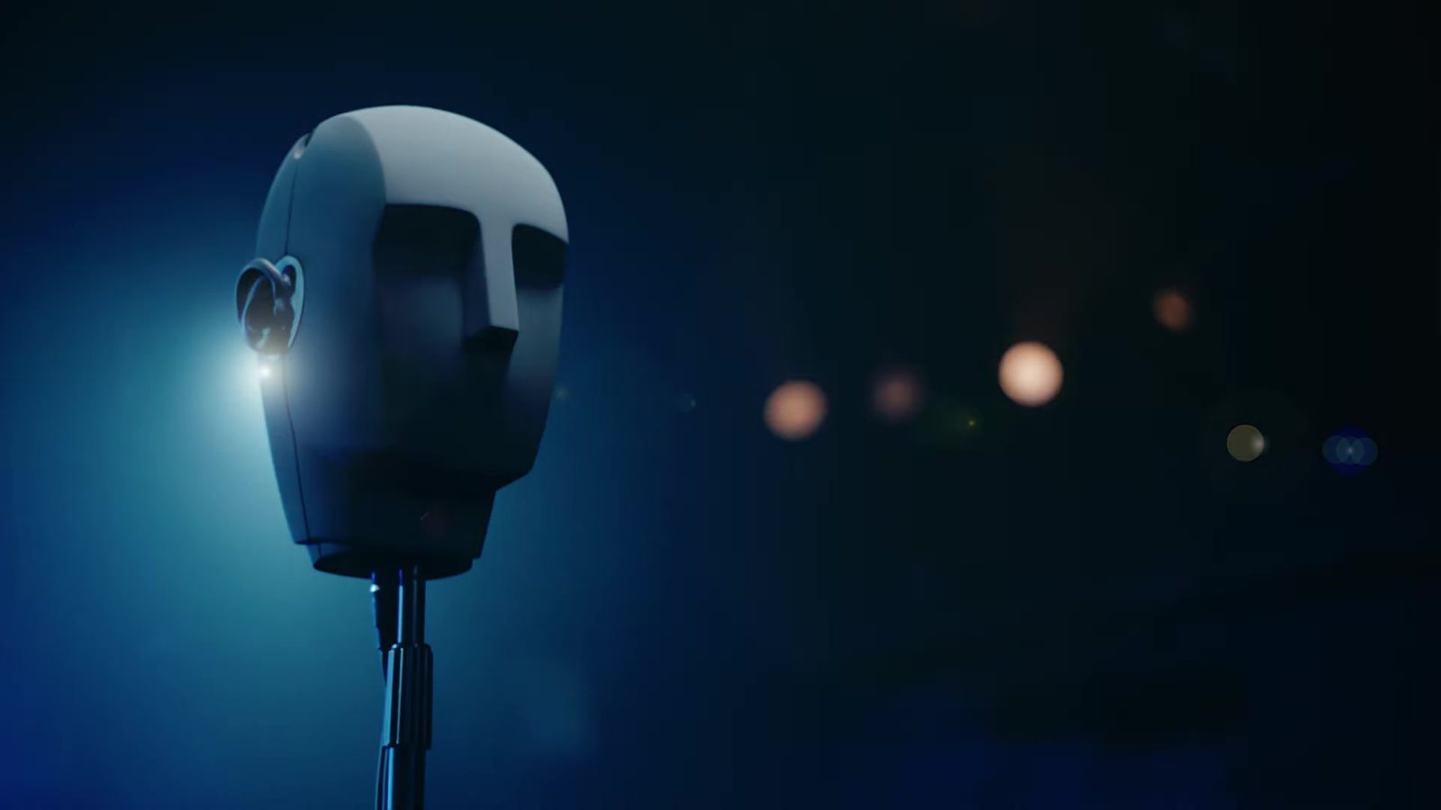 La cabeza binaural gris de A Ghost in Your Ear, iluminada en azul sobre un escenario oscuro. Imagen: Audible Theater