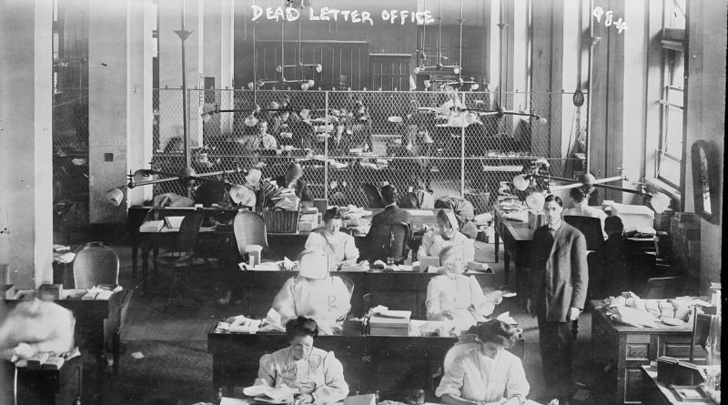 The Dead Letter Office of the US Post Office in the early 1900s: rows of clerks at desks covered in opened letters and parcels, with DEAD LETTER OFFICE written across the top of the glass negative. Image: Bain News Service, Library of Congress, public domain