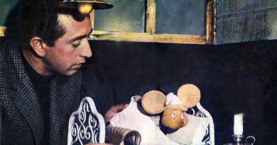 Peppino Mazzullo in 1961, in a tweed jacket, leaning over a miniature bed where the Topo Gigio puppet lies under the covers beside a small candle. Image: Radiocorriere, 1961, public domain