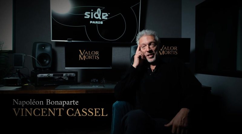 Vincent Cassel sentado en un estudio de grabación junto a un monitor de Valor Mortis, con la tarjeta Napoleón Bonaparte, Vincent Cassel. Imagen: Lyrical Games, fotograma del video oficial de entre bastidores
