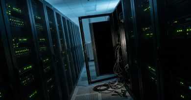 A data centre aisle at night with one server rack switched off, its door open and cables unplugged on the floor. © Voice Over Herald