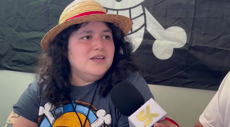 Desireé González, the Latin American voice of Luffy, wearing a straw hat in front of a Straw Hat Pirates flag during a 2023 interview. Image: SamuelitoKingdom