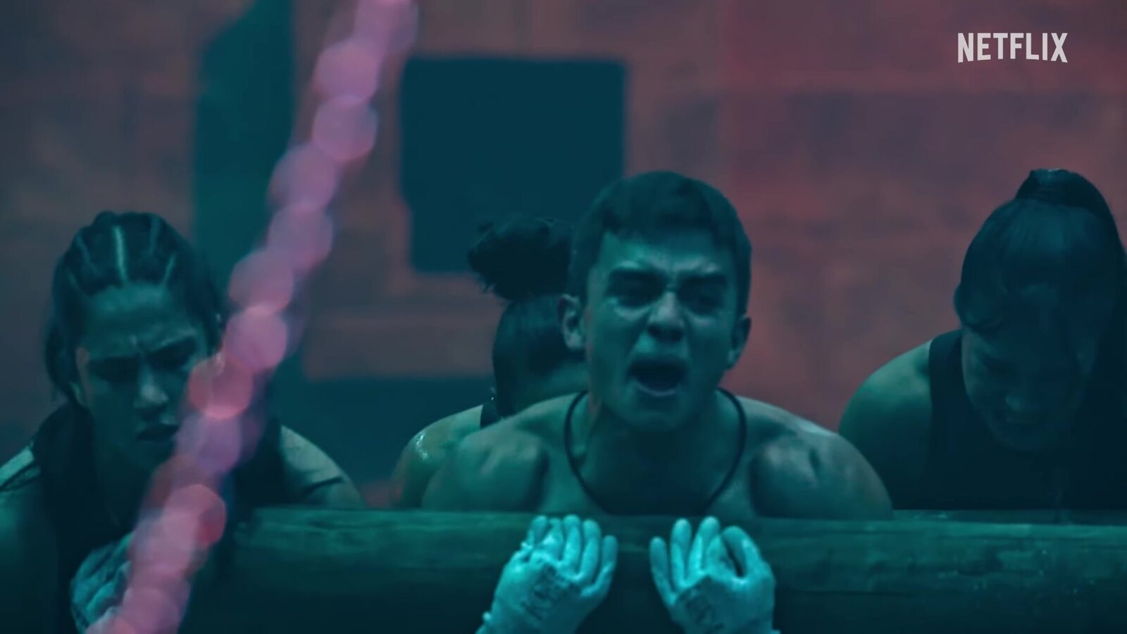 A contestant strains against a giant log in the trailer for Physical: 100 Mexico. Image: Netflix