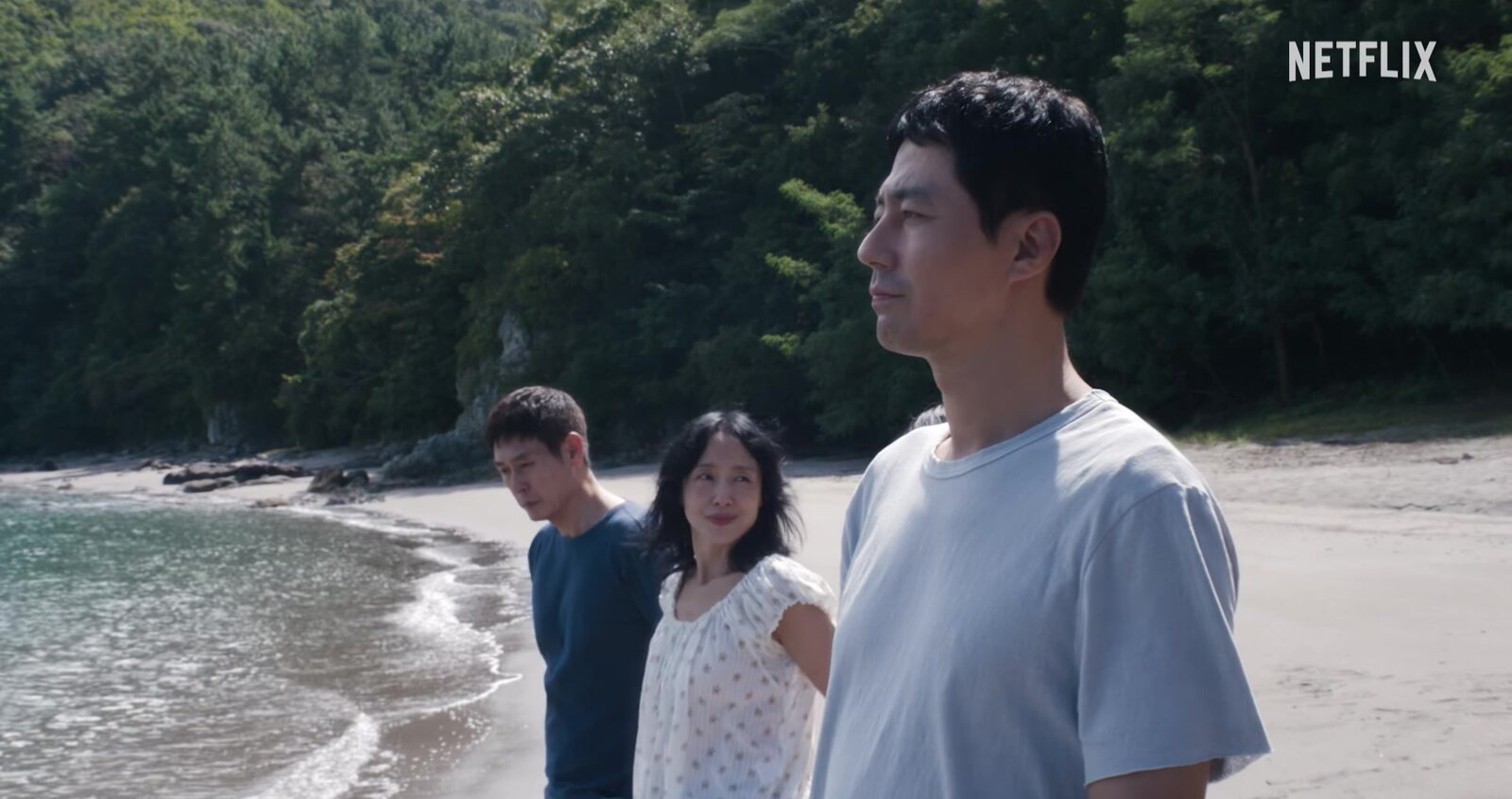 Three people stand on a beach in a still from the trailer for Lee Chang-dong's film Possible Love. Image: Netflix