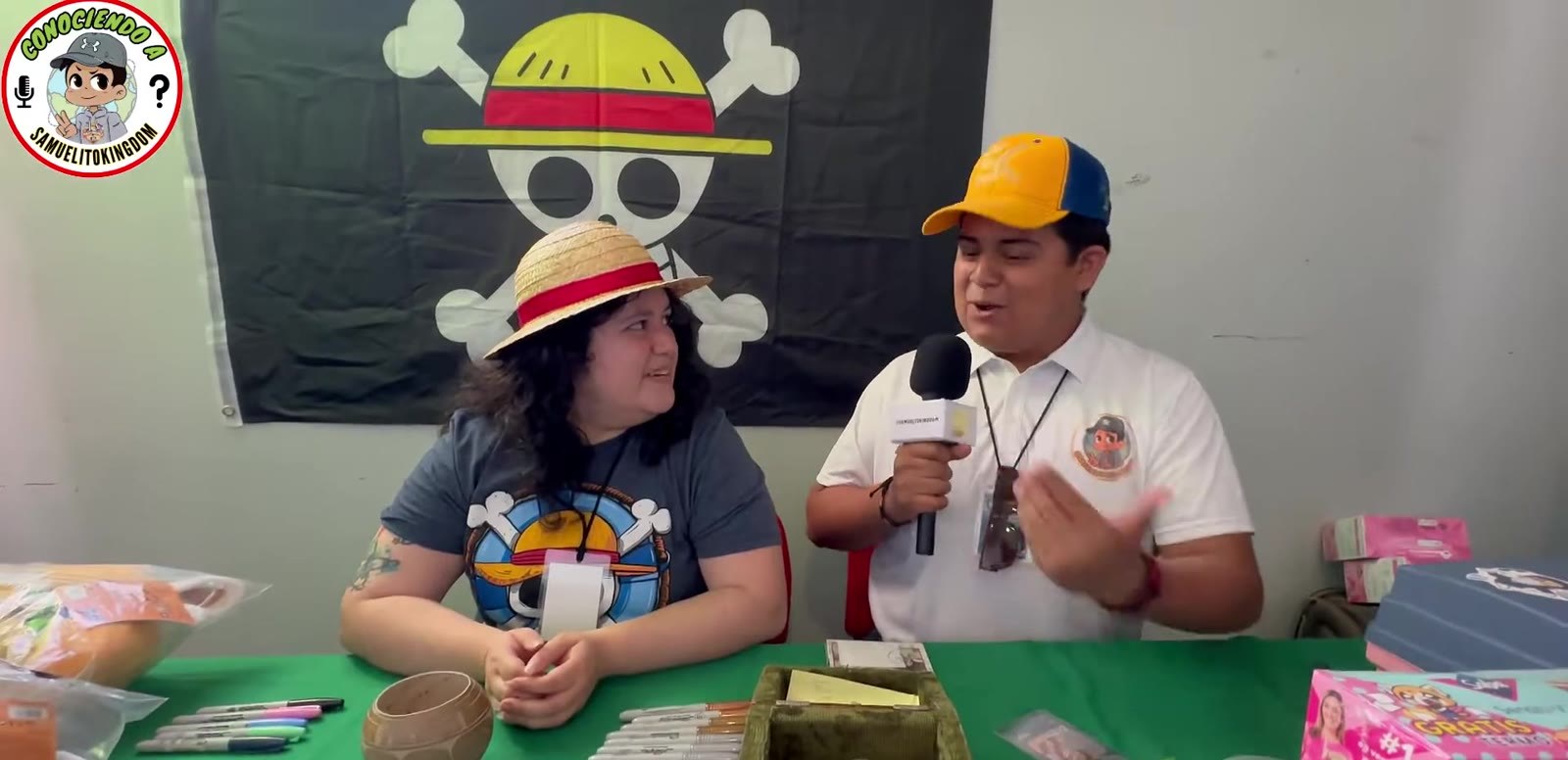 Desireé González con un sombrero de paja junto al entrevistador Samuelito, frente a una bandera de los Piratas del Sombrero de Paja, diciembre de 2023. Imagen: SamuelitoKingdom