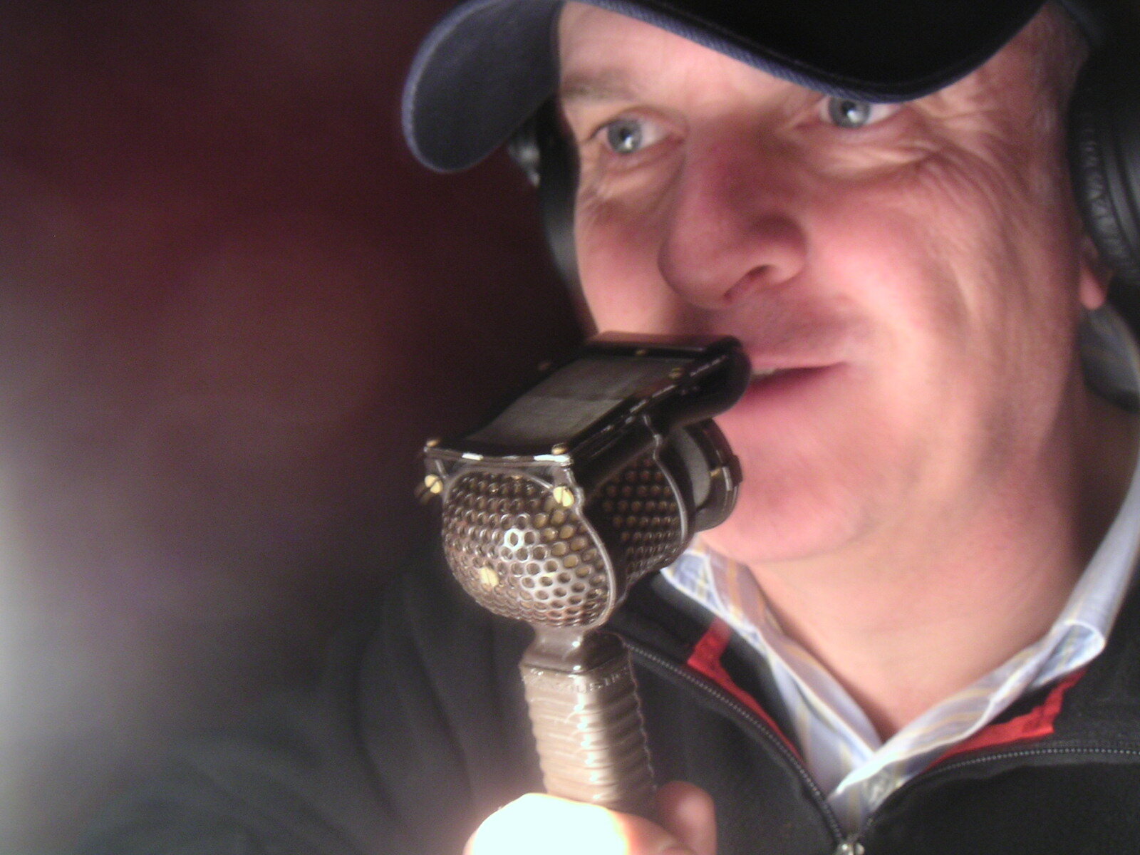 Peter Dickson in a cap and headphones speaking into a vintage microphone. Image: Peter Dickson media pack