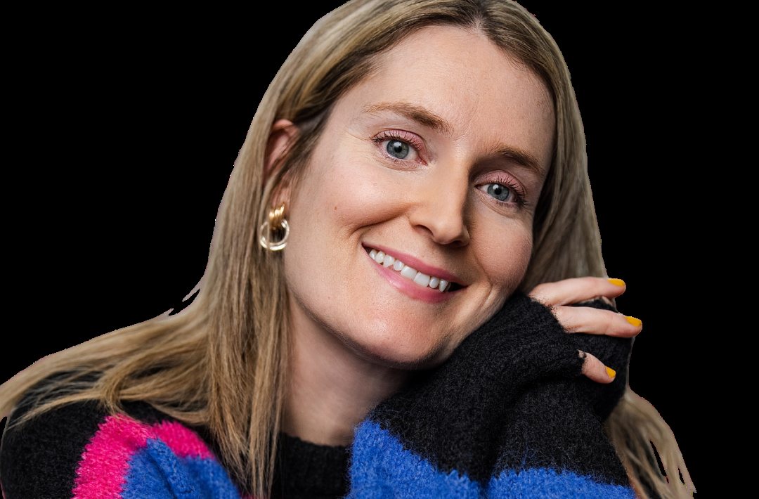 Portrait of voice actor Emily McGonagle smiling in a bright striped jumper. Image: Emily McGonagle