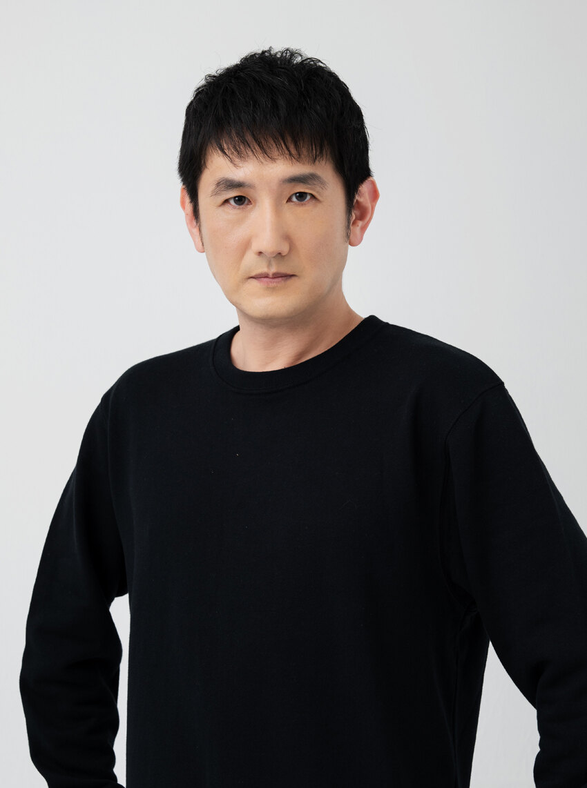Hiroshi Tsuchida, studio portrait in a black sweater against a pale grey background. Image: 81 Produce