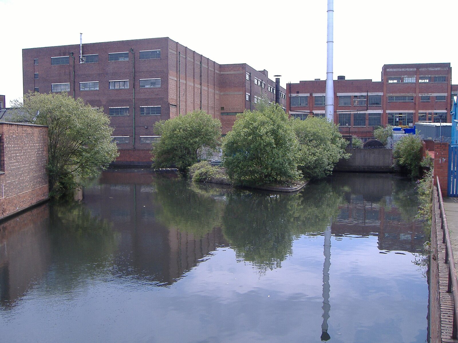 The red brick former Typhoo tea factory in Digbeth, Birmingham, with a tall chimney, reflected in a canal basin, photographed in 2006.