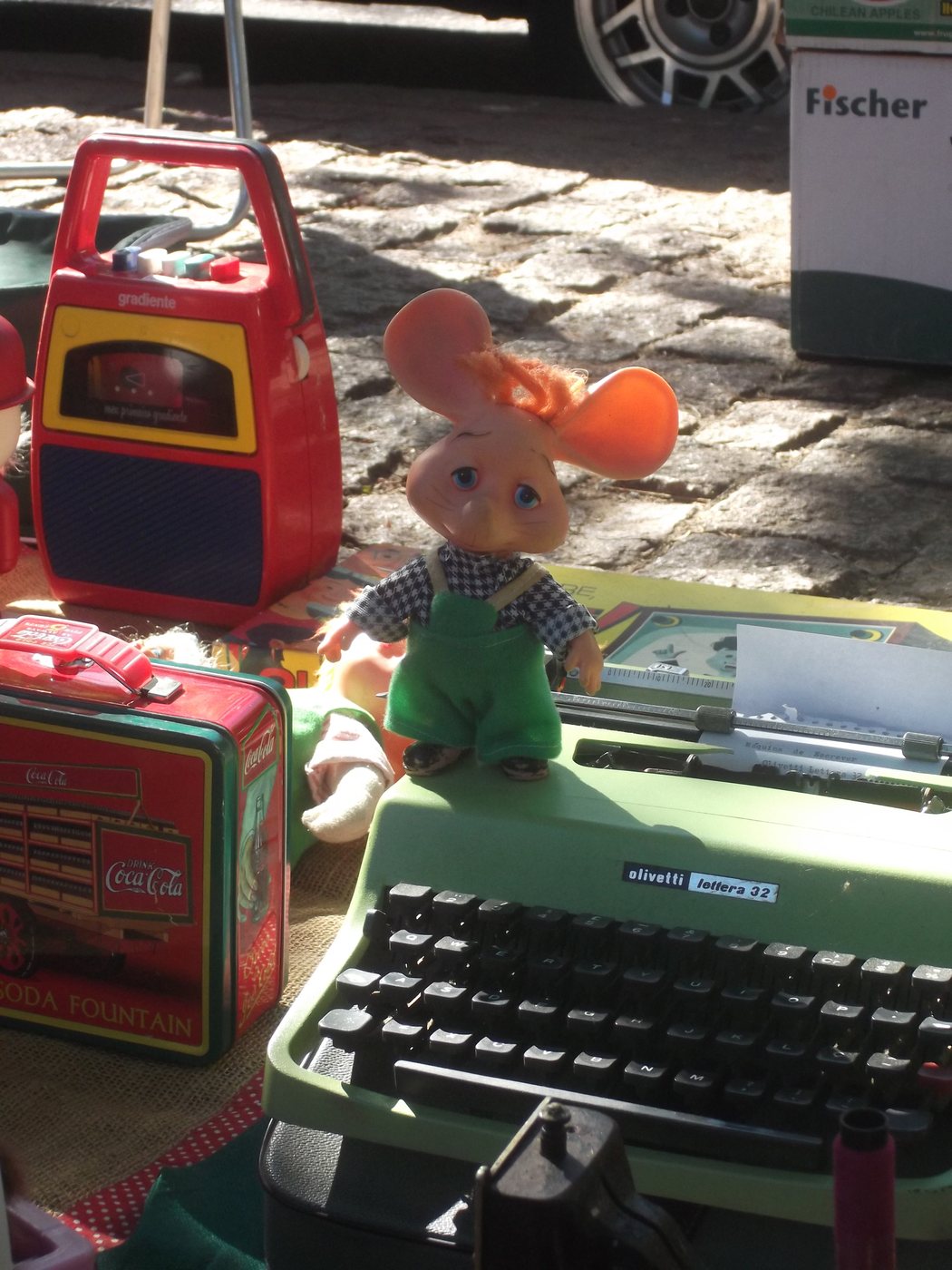 A Topo Gigio toy in green overalls stands on a green Olivetti typewriter at a Sunday flea market stall in Porto Alegre, Brazil. Photo: Eugenio Hansen, OFS, CC BY-SA 3.0
